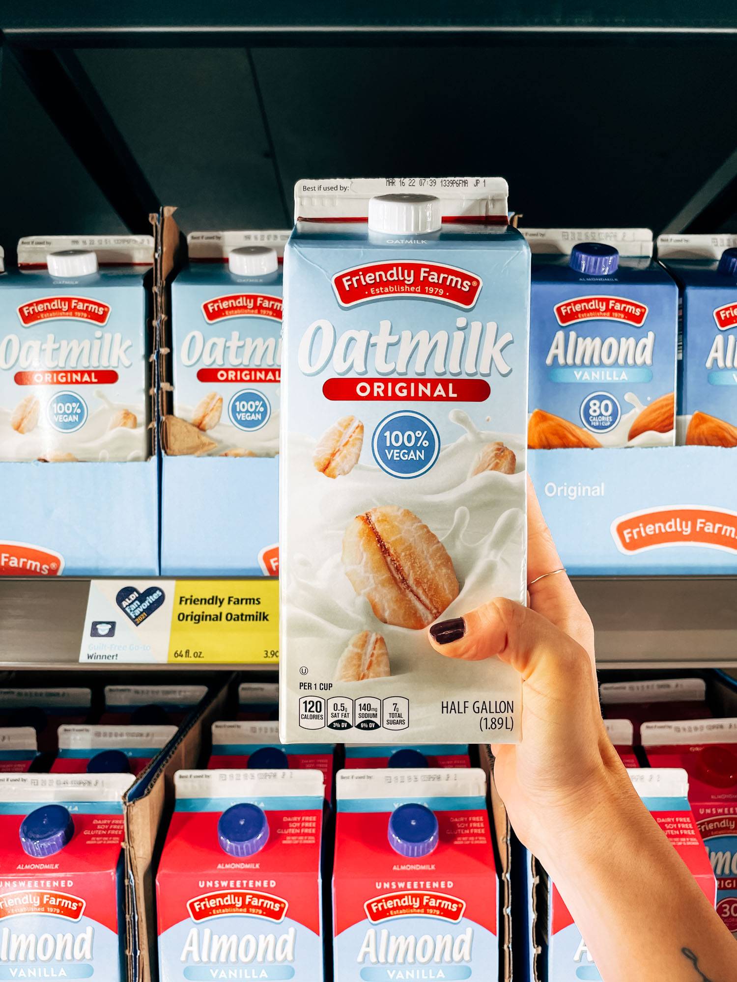 Mano blanca sosteniendo un cartón de leche de avena